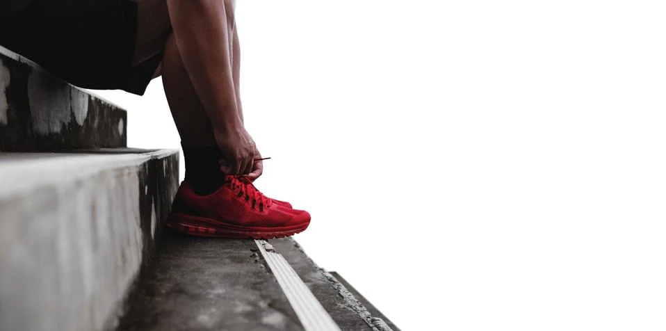 Close-up runner tying shoelace on the steps, isolated on white background Foto stock