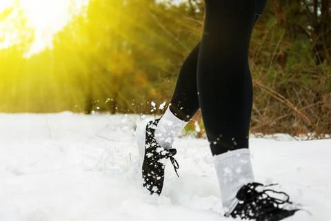 Close up of runner's legs jogging through winter snow. Athlete in black tig.. Foto stock