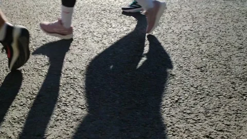 Close-up of runners legs in motion with shadow cast Video stock 307168469