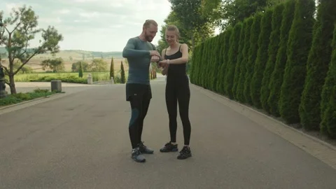 Close up running athlete man and woman looking at smartwatch talking fitness Stock Footage 138634230