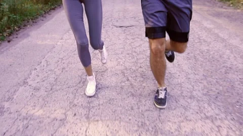Close-up of running couple on a paved road Stockbeeldmateriaal 68057682