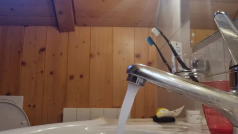 Close-up of a running faucet with crystal-clear potable water flowing in a Vidéo 304598593