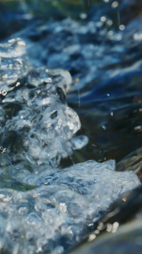 Close-up of rushing water with frothy bubbles and sunlight reflections Stock Footage 335568161