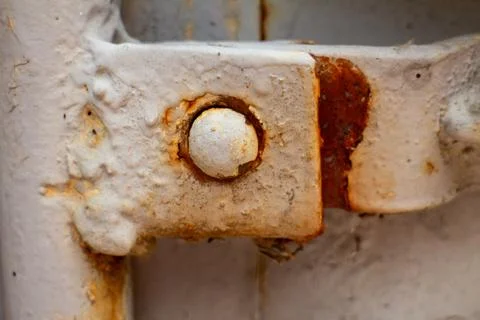 Close-up of a rusted metal hinge with old white paint on an industrial door 库存照片