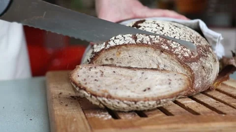 Close Up of Rustic Bread Loaf Sliced with Serrated Knife on Board Stock Footage 298167623