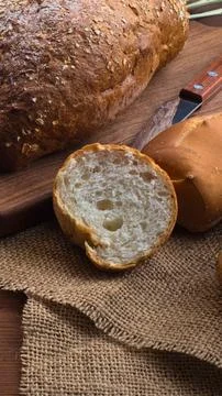 Close up of a rustic bread roll cut in half on burlap Stock Photos