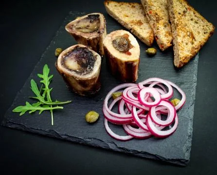 Close-up of rustic English bone marrow with toast, capers and onions Stock Photos