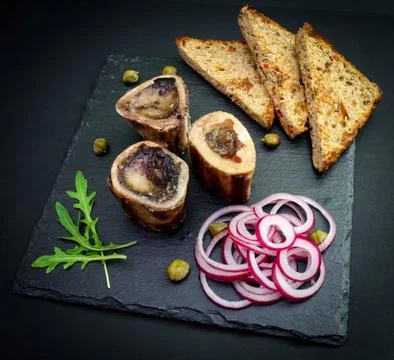 Close-up of rustic English bone marrow with toast, capers and onions Stock Photos