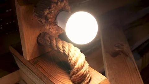 Close-up of Rustic Interior Lighting Fixture with Thick Rope and Bright Bulb Stock Footage 323183196