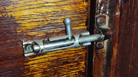 Close-up of rustic metal barrel bolt lock securing aged wooden door. Vintage Stock Photos