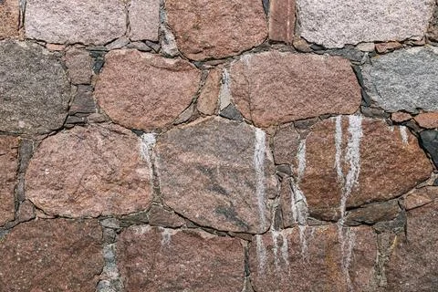 Close-up of a rustic stone wall, likely built with granite or a similar typ.. Stock Photos