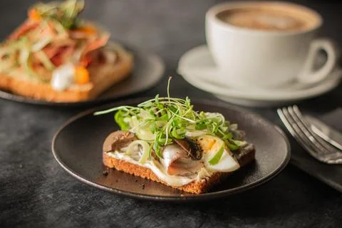 A close-up of a rustic toast topped with herring, boiled egg, greens Foto stock