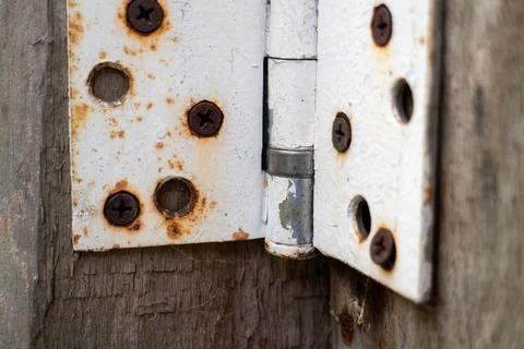 Close-up of a rustic, weathered door hinge with rust and peeling white paint Stock-Fotos