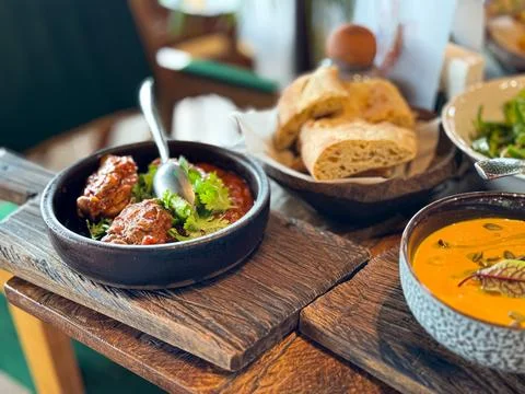 Close up of rustic wooden table with braised meat in tomato sauce garnished with Stock-Fotos