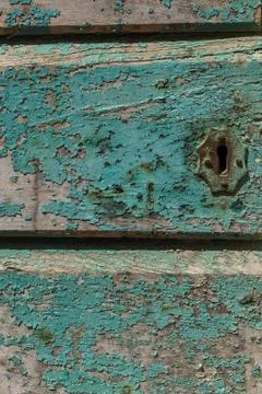 A close up of a rusting key hole on a painted wooden door, the aqua blue paint Stock Photos
