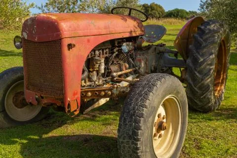 A close up of a rusting red tractor sitting in a garden Stock Photos
