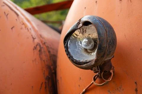 Close-up of a rusty and damaged headlight with a visible bulb on an old vehic Stock Photos
