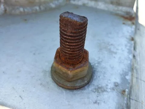 Close up of a rusty bolt with grey cement in the background Stock Photos