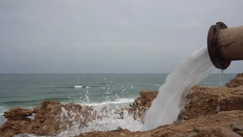Close-Up of Rusty Industrial Pipe Discharging Wastewater on Rocky Ocean Coast Vídeos de archivo 334182583