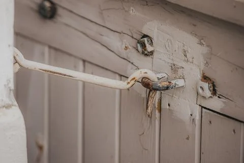 Close-up of a rusty metal latch attached to a weathered wooden door with pe.. Stock Photos