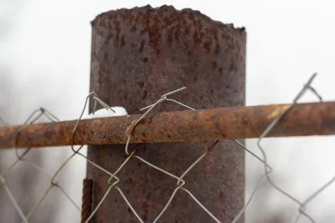 Close-up on a rusty metal pole rusty steel mesh chain link.An old fence. Stock Photos