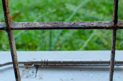 Close Up of Rusty Metal Window Grille with Green Nature Background Stock Photos