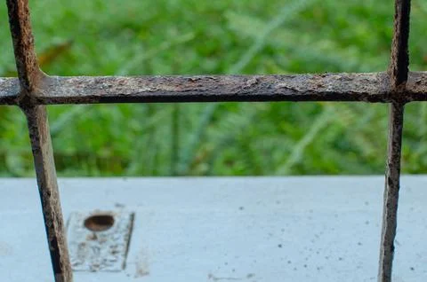 Close Up of Rusty Metal Window Grille with Green Nature Background Stock Photos