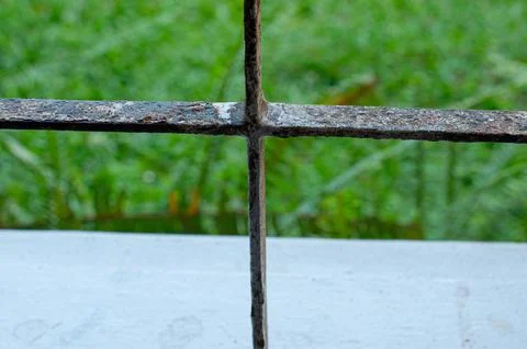 Close Up of Rusty Metal Window Grille with Green Nature Background Stock Photos