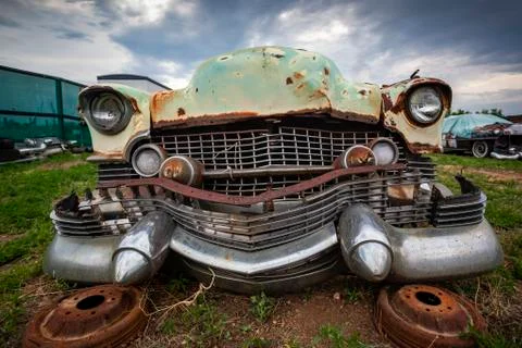 Close up on a rusty old classic car front, abandoned with broken parts in the Stock Photos