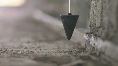 Close-up of rusty plumb bob hung along concrete wall Stock Footage 123790617