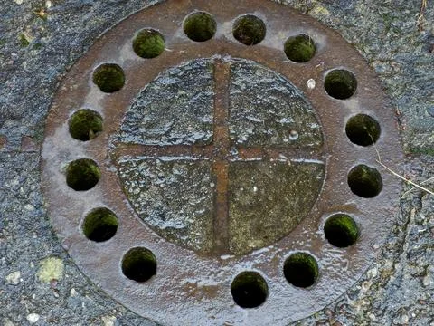 Close-up of a rusty round cast iron manhole cover with drainage Fotos de archivo