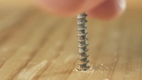 Close-up rusty self tapping screw screwing into wood by man using hands. Macro Stock Footage 309328306