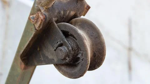 Close-up of a rusty, worn metal roller guide mechanism. Stock Photos