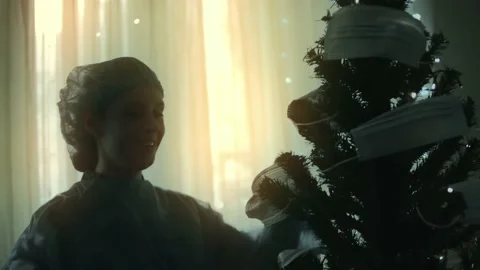 Close-up of the sad doctor in protective suit and visor looking at the Christmas Stock Footage 145471258