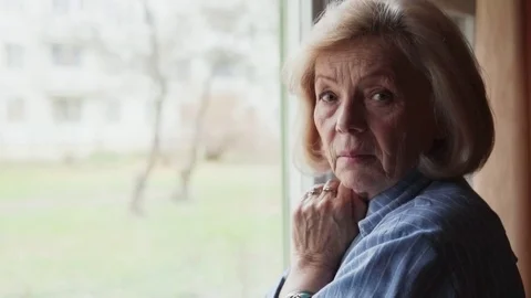 Close-up of sad old woman turning head and looking Stock Footage