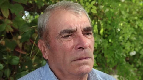 Close-up of sad thoughtful senior man’s face sitting in the garden Stock Footage 81657764