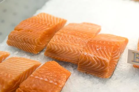 Close up of salmon fillets spread over ice on a fish mongers market stall Stock Photos