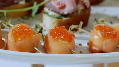 Close up salmon rolls garnished with red caviar, green herbs resting on Stock-Fotos