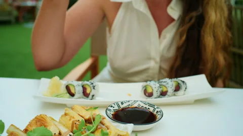 Close-up of salmon sashimi with a woman eating sushi in the background Stock Footage 344793853