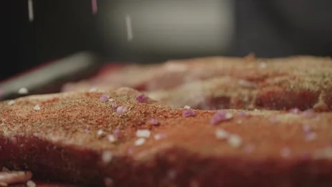 Close-up of salt crystals falling on a piece of pork ribs. Stock Footage 234920279