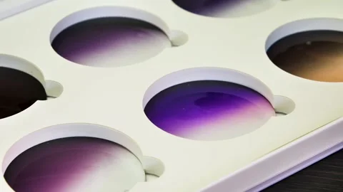 Close-up of sample tinted lenses in a display case at a lenses factory in Video stock 290525099