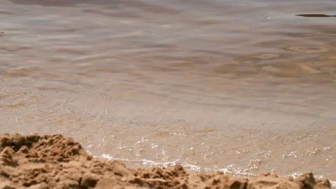 Close up of sand and river wave. River surface reflecting the rays of the Stock Footage 149692643