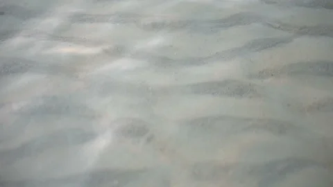 Close Up of Sand Being Swirled Up Into Shallow Water By Ocean Waves Near Beach Stock Footage 120331457