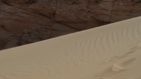 Close up on sand blowing down a dune next to a rock formation Stock Footage 90918367
