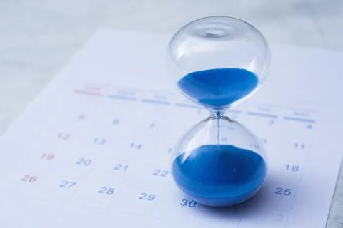 Close up of sand clock on paper monthly calendar background. Professional i.. Stock Photos