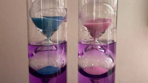 Close Up Of Sand Falling Inside Blue And Pink Hourglass Timers Stock Footage 321724454