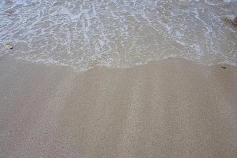 Close-up of sandy beach with gentle ocean waves Stock Photos