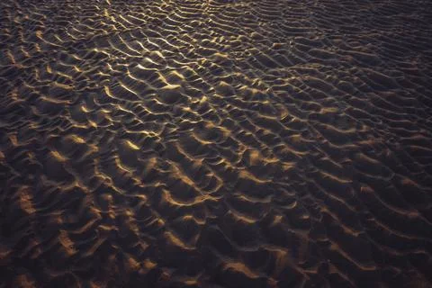 Close-up of sandy ripples creating a mesmerizing pattern under the warm sunset Stock Photos