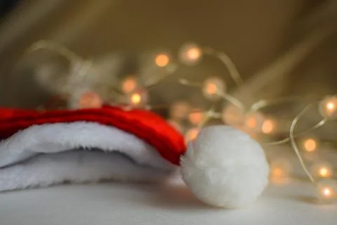 Close-up of a Santa Claus hat set against the glow of string lights Stock Photos