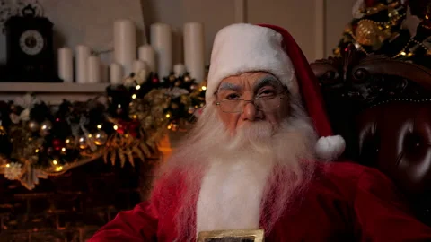 Close up Santa Claus looks camera sitting on chair at home, Christmas holidays Stock Footage 166559064